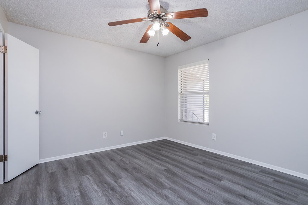 A room with a ceiling fan and a window with blinds.