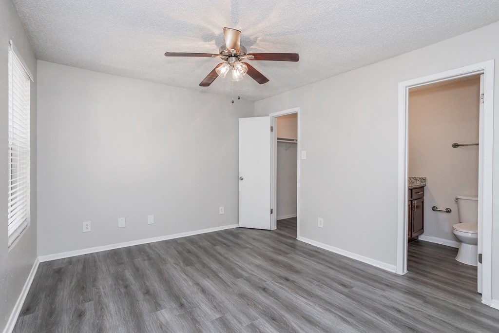 A room with a ceiling fan and a toilet in the corner.