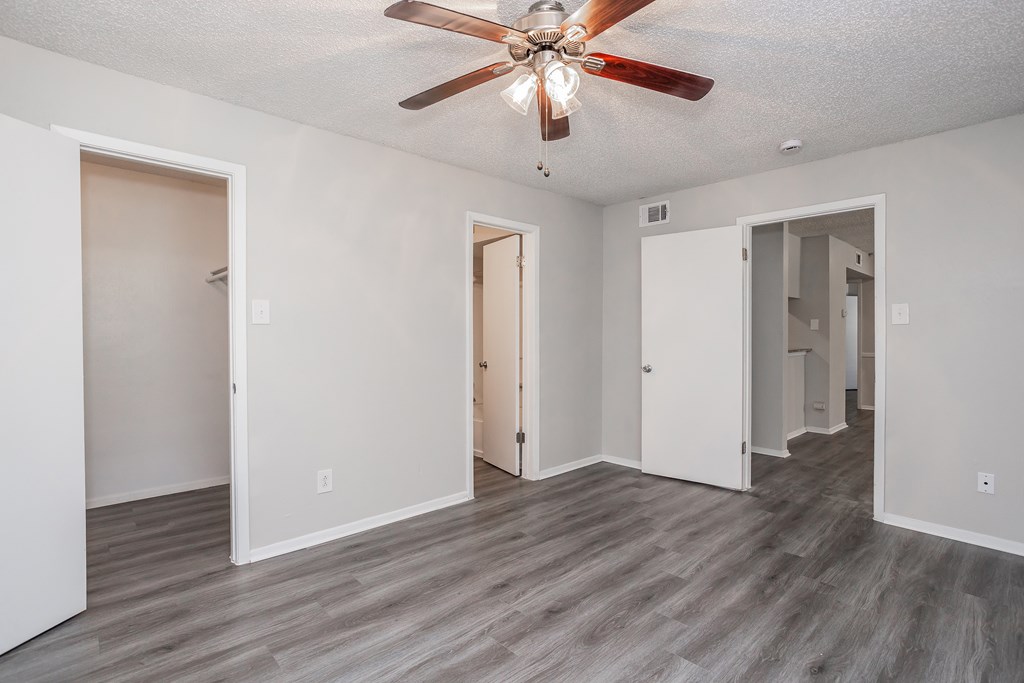 A room with a ceiling fan and wooden flooring.
