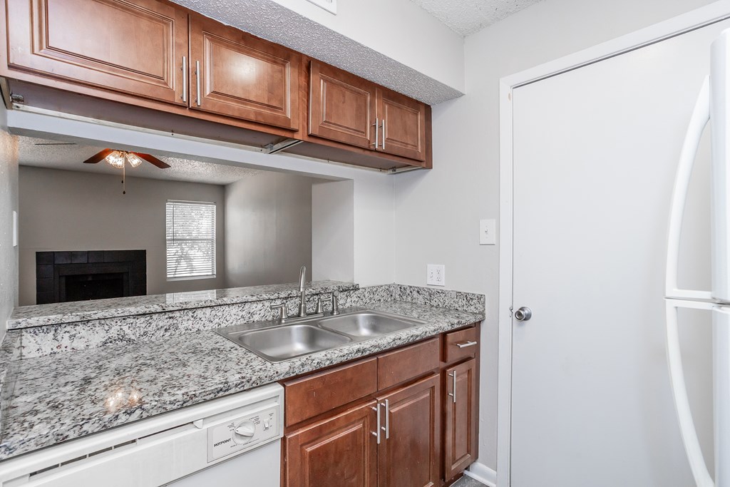 A kitchen with brown cabinets and a granite countertop.