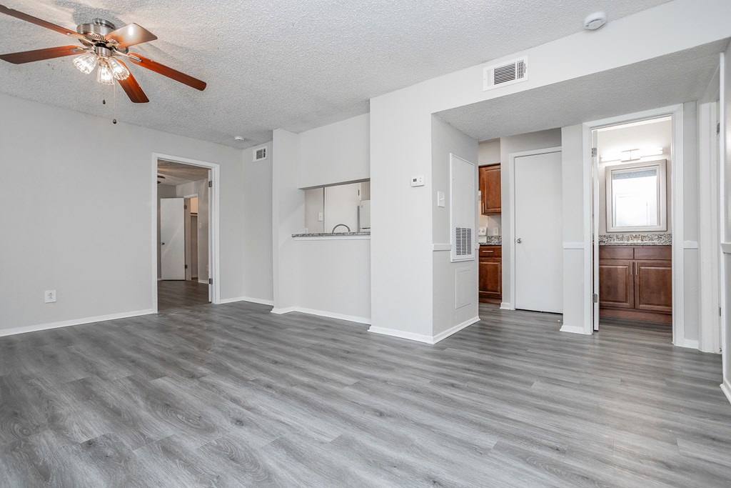 A spacious room with a ceiling fan and lighting fixture.