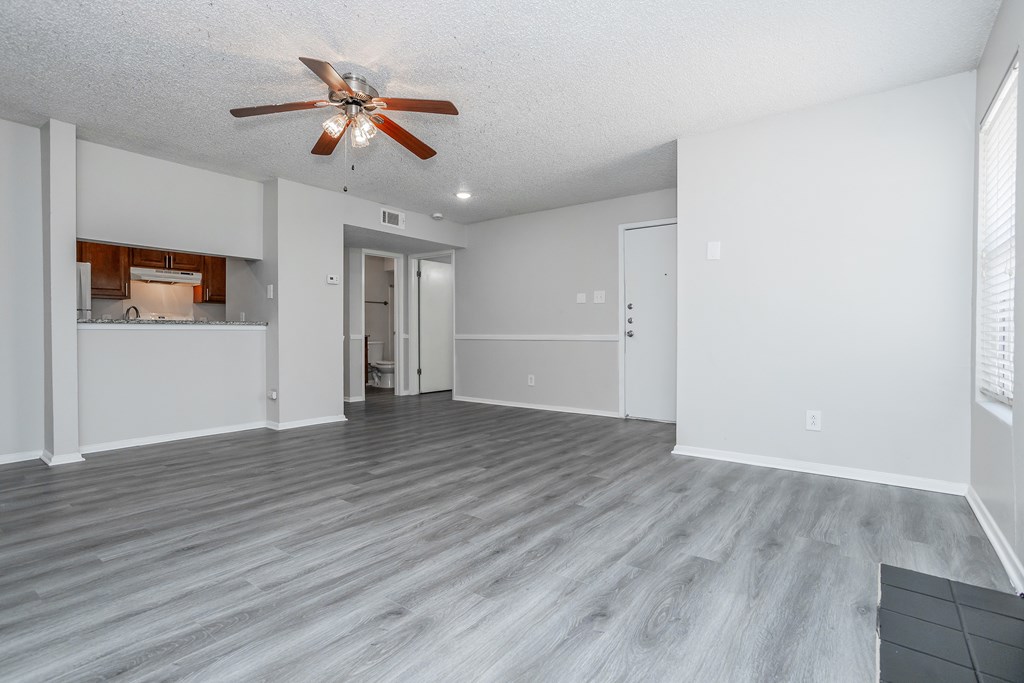 A room with a ceiling fan and wooden flooring.