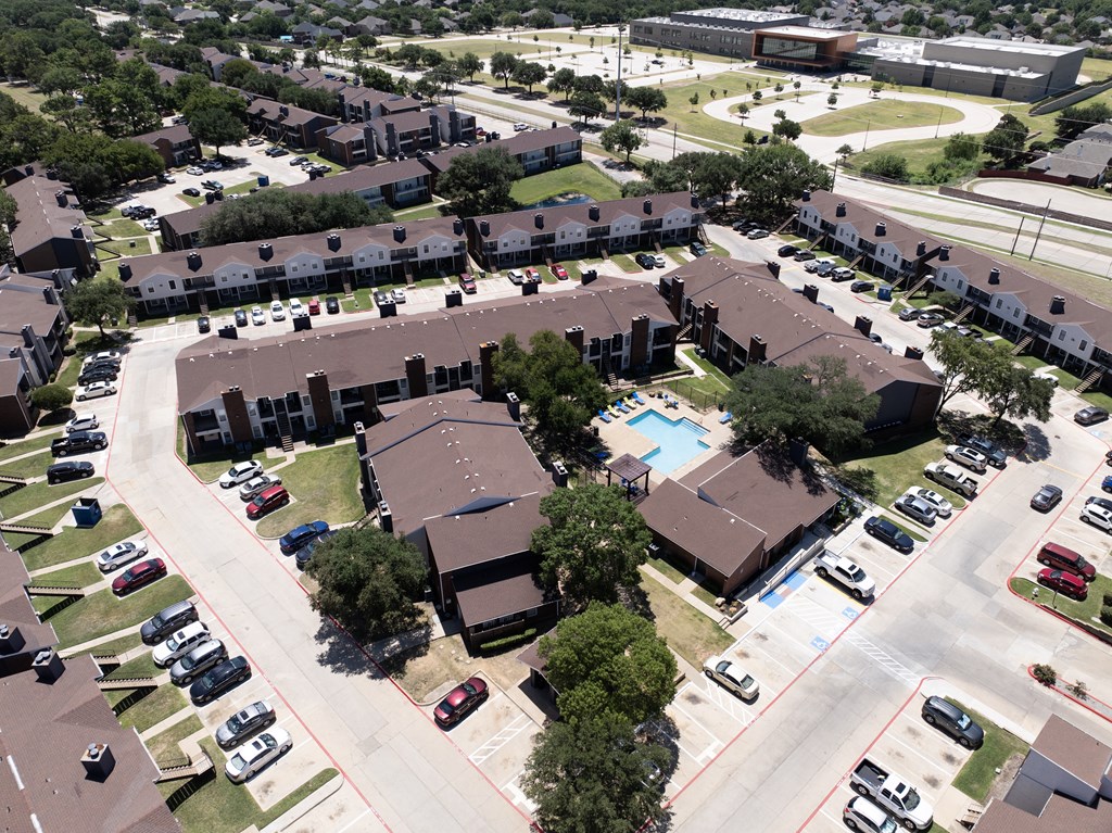 A bird's eye view of a residential area with houses, cars, and a swimming pool.