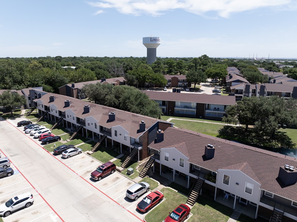A parking lot with cars and a building with a tower in the background.