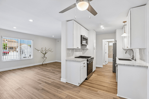 A modern kitchen with white cabinets and a wooden floor.