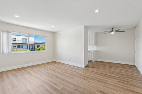 A spacious room with wooden flooring and a ceiling fan.