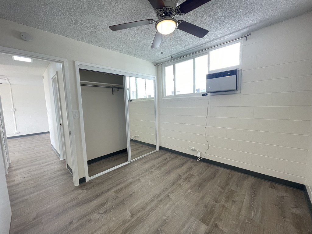 an empty living room with a ceiling fan and a closet