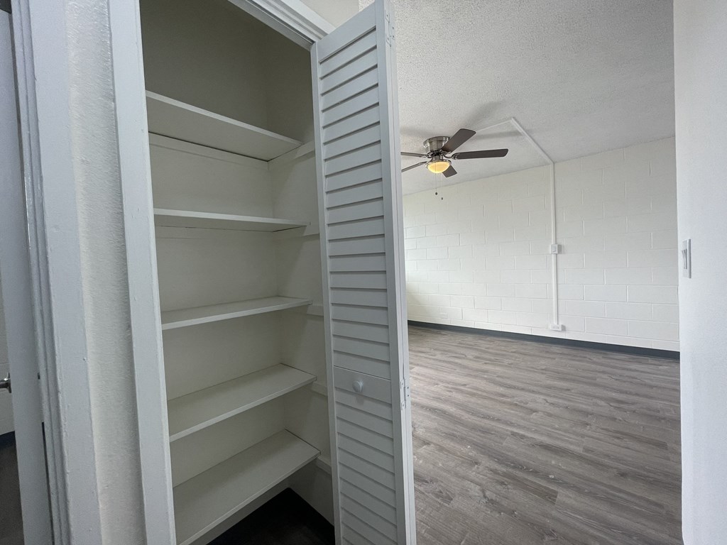 an empty closet in an empty room with a ceiling fan