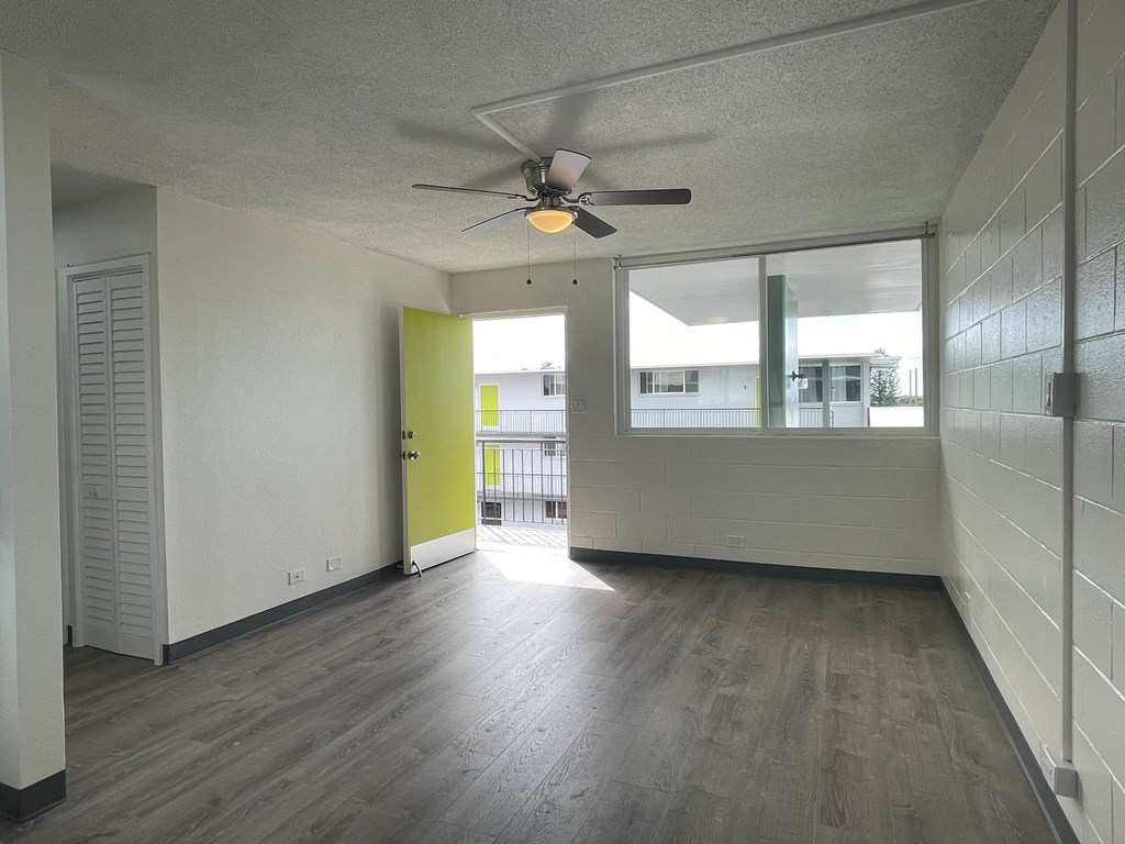 an empty living room with a ceiling fan and a window