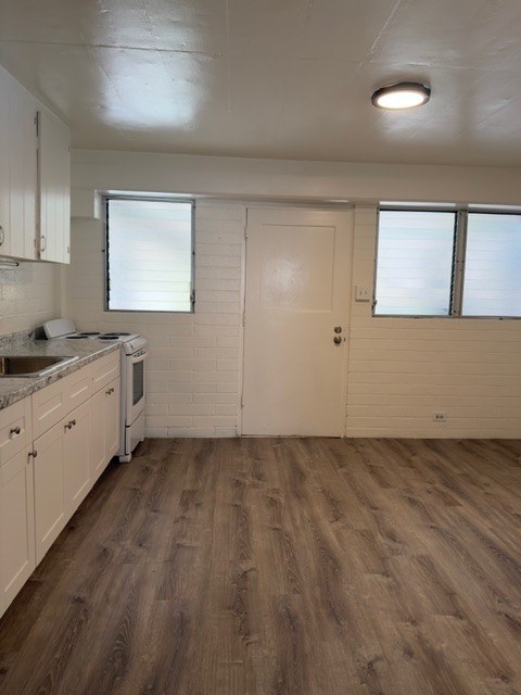 A kitchen with white cabinets and a wooden floor.