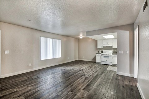 an empty living room and kitchen with wood flooring