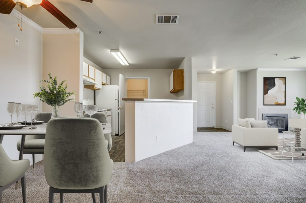 A modern living room with a grey carpet and a dining table set for two.