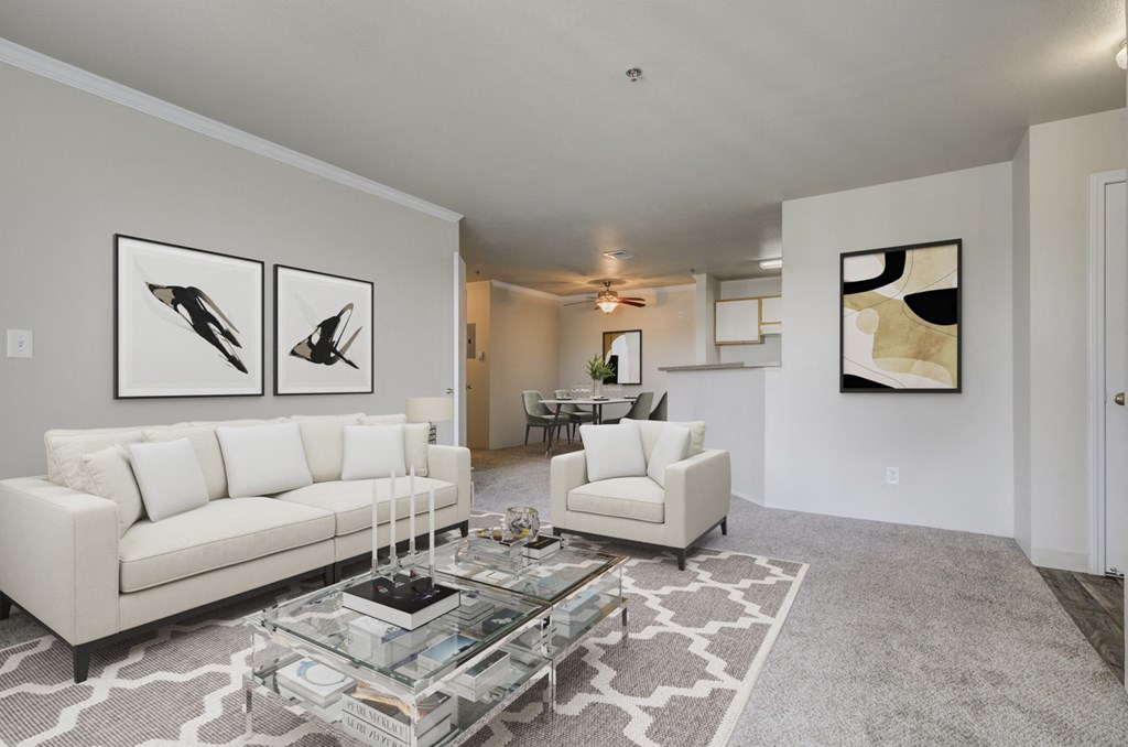 A living room with a white couch, a coffee table, and two framed pictures on the wall.