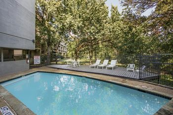 a swimming pool with chairs and a building in the background