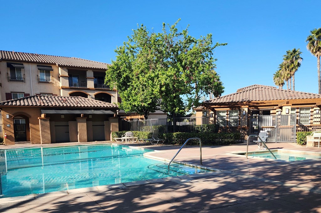 A swimming pool in front of a building with a tree in the background.