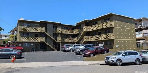 A multi-story building with a parking lot in front.