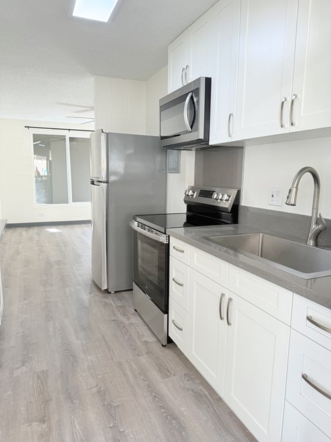 A kitchen with white cabinets and a black countertop.