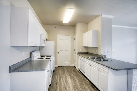 A kitchen with white cabinets and a white stove top oven.
