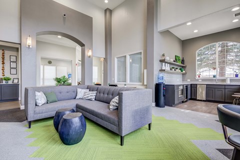 A living room with a grey couch and a blue vase.
