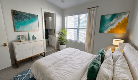 A bedroom with a large bed and a painting on the wall.