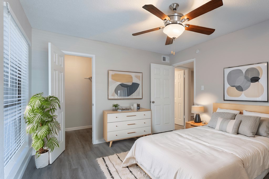 A bedroom with a bed, dresser, and ceiling fan.