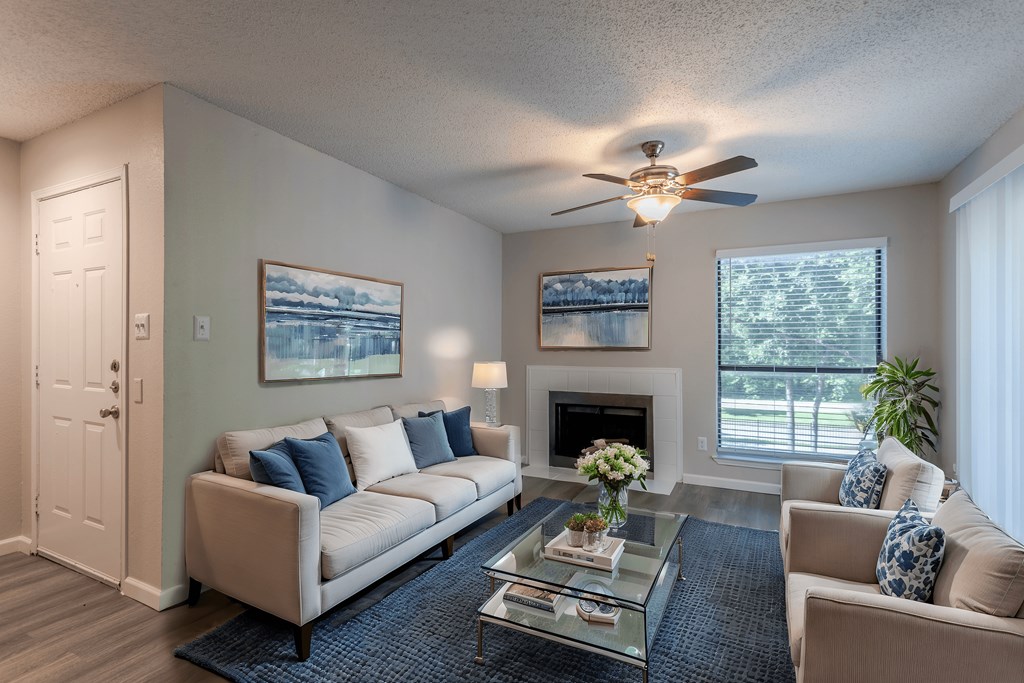 A living room with a white couch, a coffee table, and a ceiling fan.