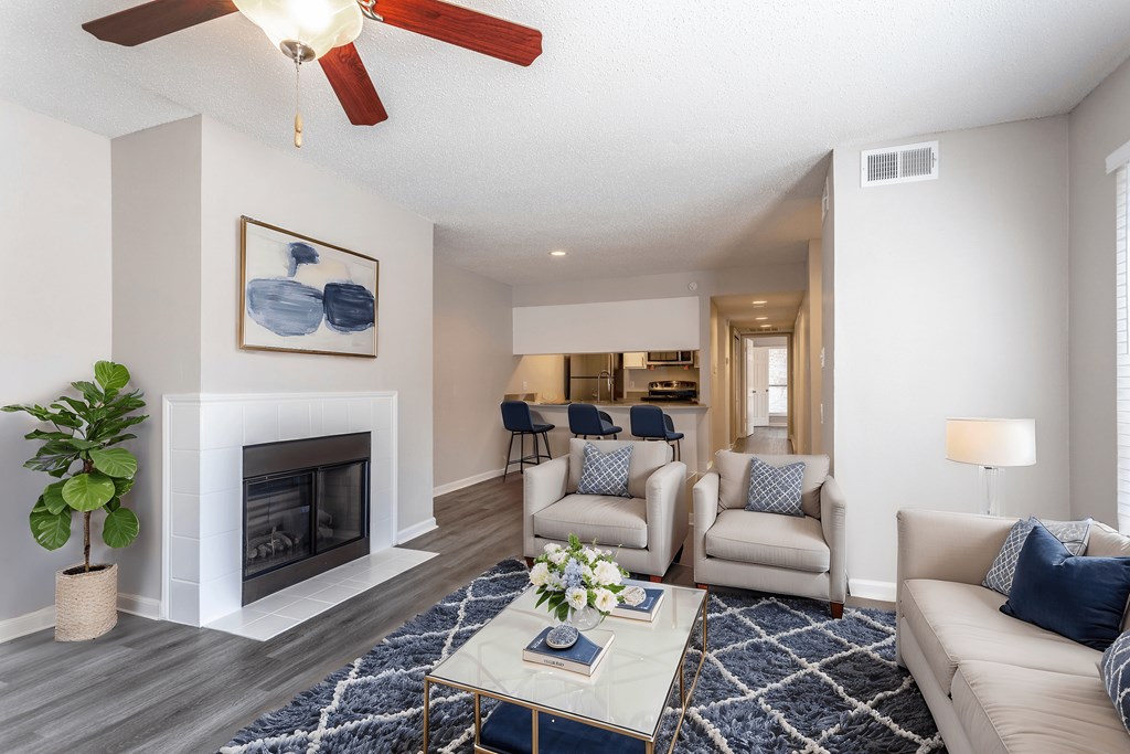 A living room with a fireplace, a ceiling fan, and a painting on the wall.