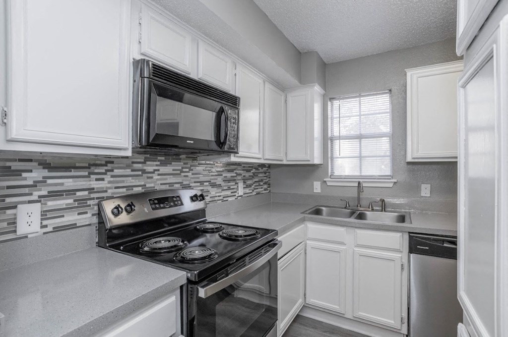 A modern kitchen with white cabinets and stainless steel appliances.