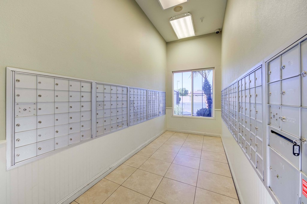 A room with a long row of mailboxes on both sides and a window in the middle.