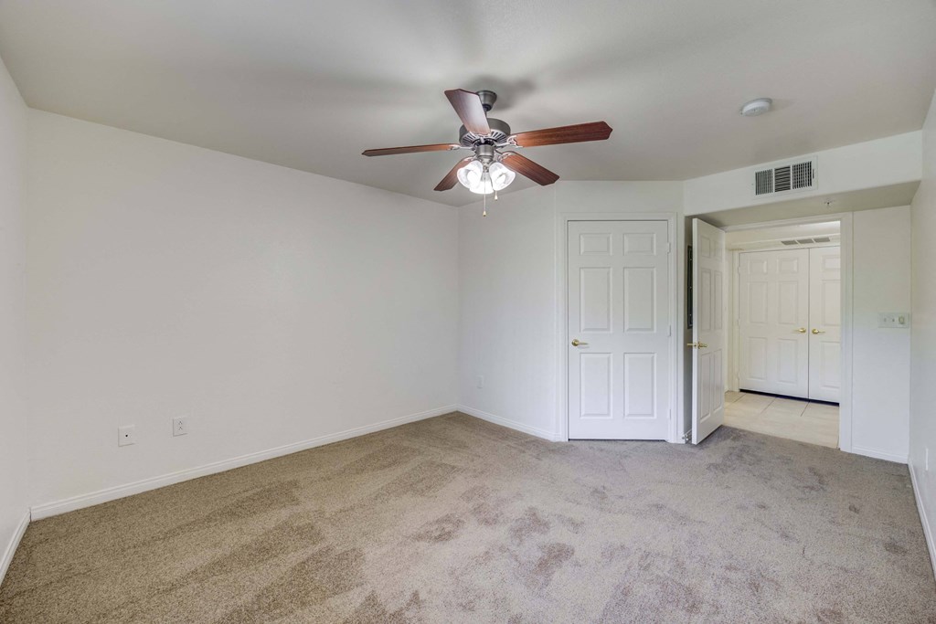 A room with a ceiling fan and carpeted floor.