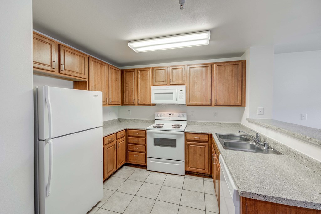 A kitchen with white appliances and wooden cabinets.