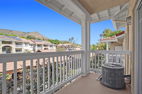 A balcony with a white railing and a grey trash can.