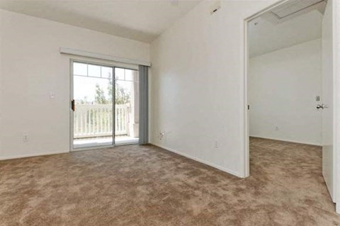 an empty living room with a door to a balcony