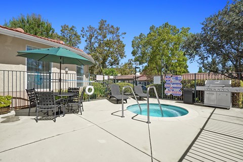 A patio with a table and chairs and a pool.