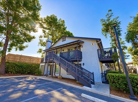 A modern two-story house with a balcony and stairs leading to the entrance.
