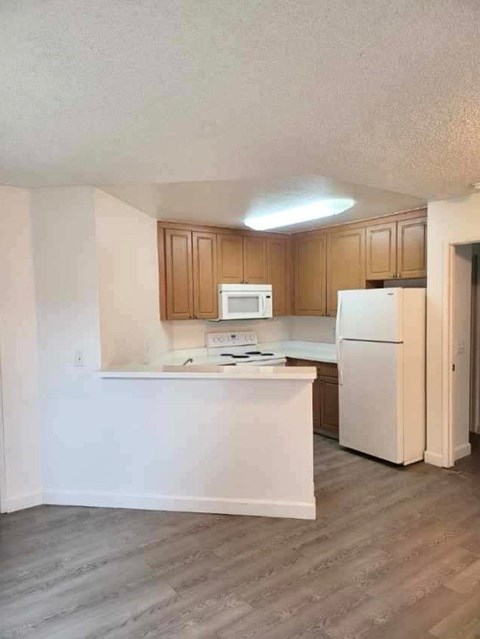 A kitchen with a white counter and a white fridge.
