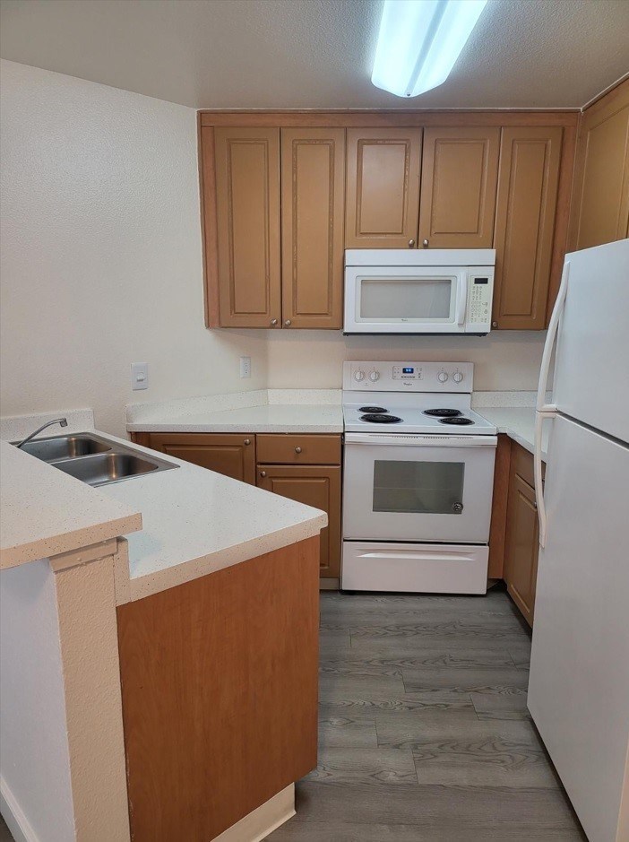 A kitchen with white appliances and wooden cabinets.