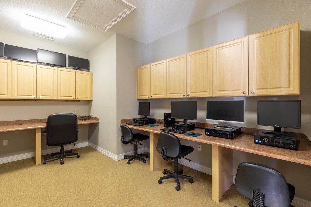 A room with a desk and chairs and a computer.