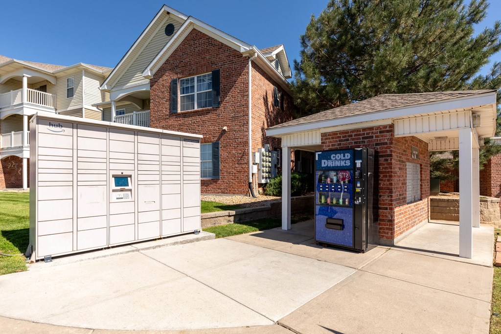 A white garage door is on the left and a brick building with a sign that says Cold Drinks is on the right.