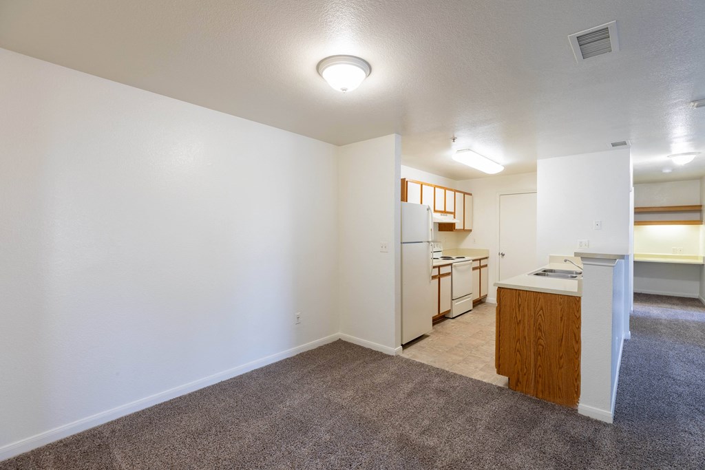 A well-lit, empty room with a kitchenette in the corner.