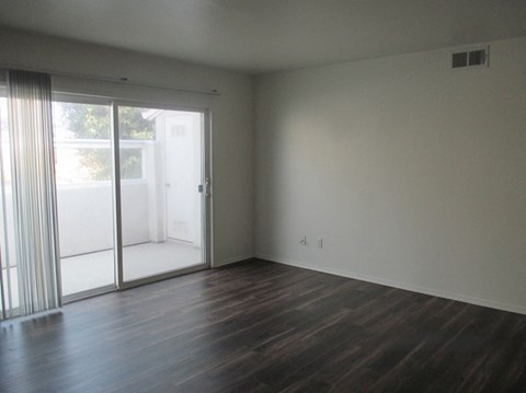 an empty living room with wood floors and sliding glass doors