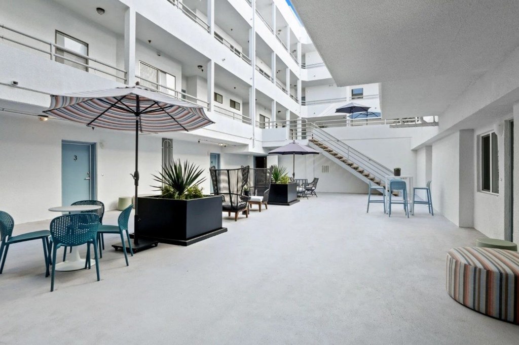 A patio area with a table and chairs and a striped couch.
