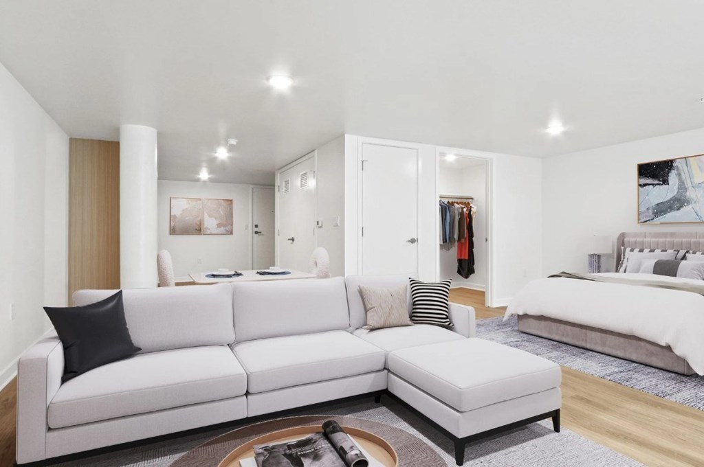 A white couch with a black pillow is in the middle of a room.