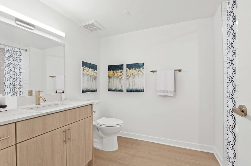 A white bathroom with a toilet, sink, and two pictures on the wall.