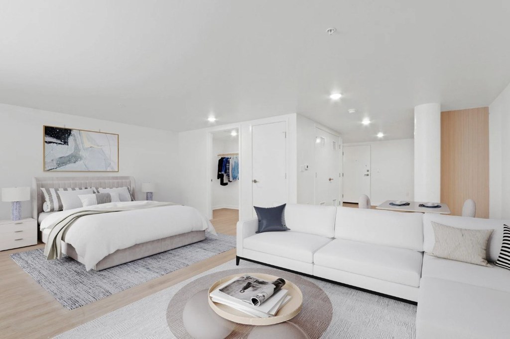 A modern bedroom with a large bed and a white couch.