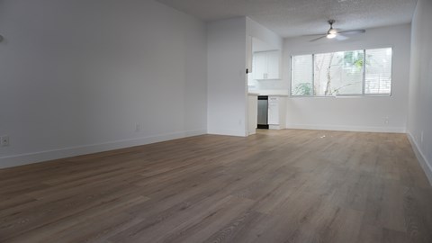 an empty living room with wood floors and a window