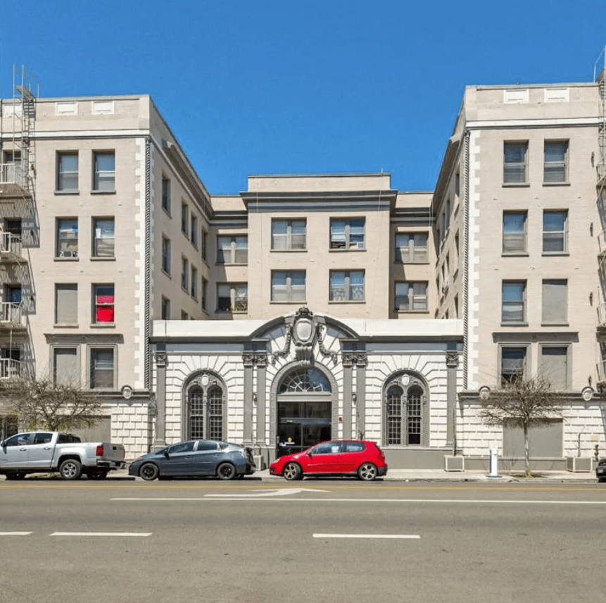 a large building with cars parked in front of it on a city street