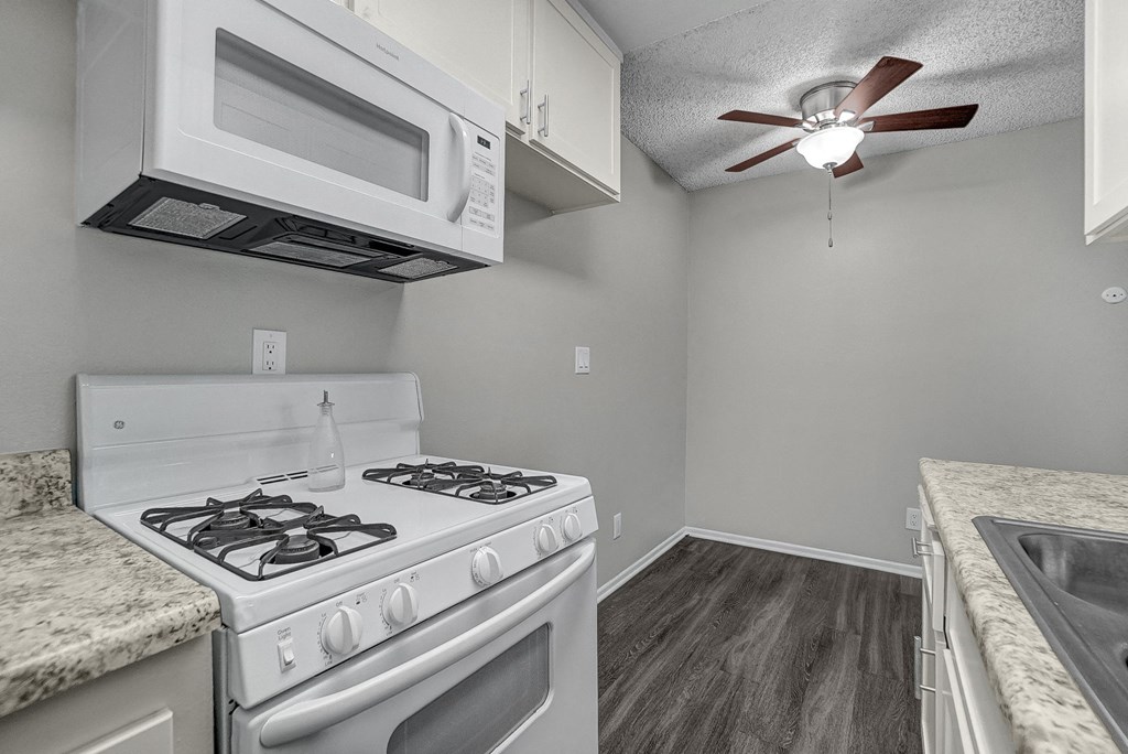 a kitchen with white appliances and a ceiling fan
