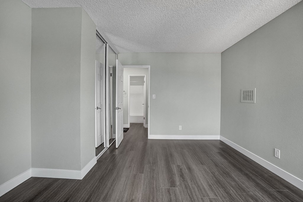 an empty bedroom with hardwood floors and grey walls