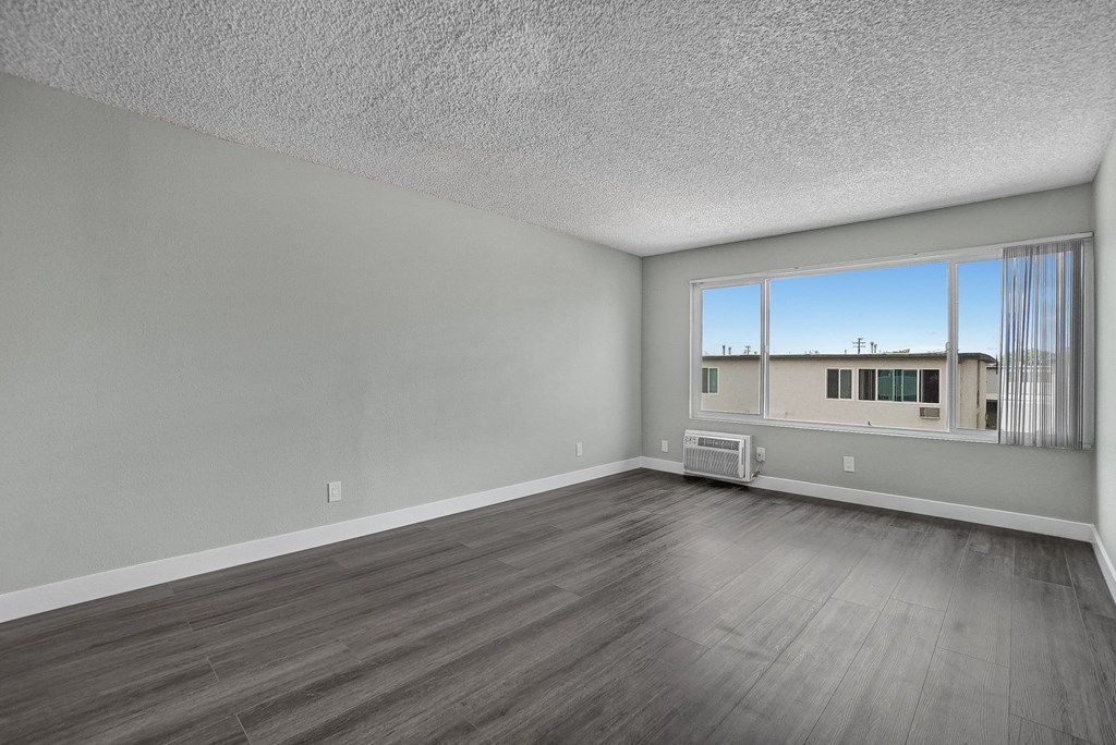a bedroom with hardwood floors and a large window